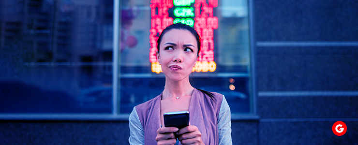 A woman holding a cell phone, looking at the screen with a smile on her face.