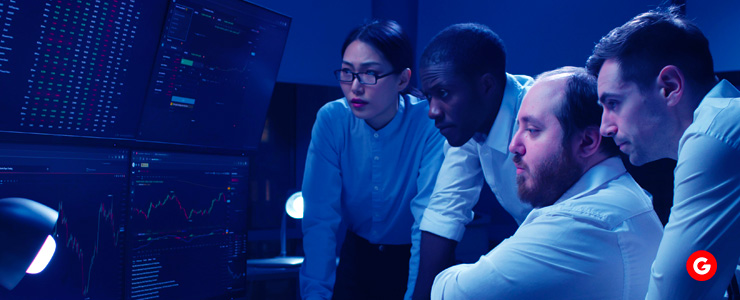 Traders observing a computer screen together, showing interest and concentration