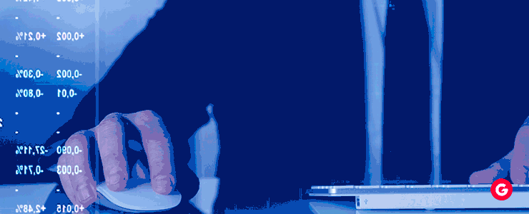 A day trader in a suit is focused on using a computer mouse at their trading station.