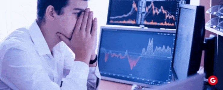 A man with his hands on his face sits in front of a computer screen, conveying a sense of contemplation or stress.