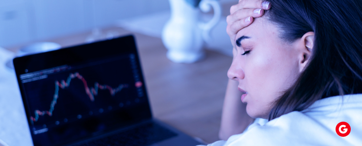 A woman gazes intently at a laptop screen displaying a stock chart, analyzing market trends and data.