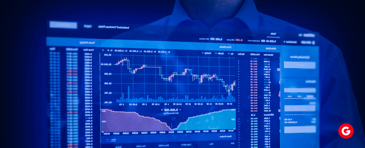 A man gazes intently at a screen displaying a fluctuating stock market graph.