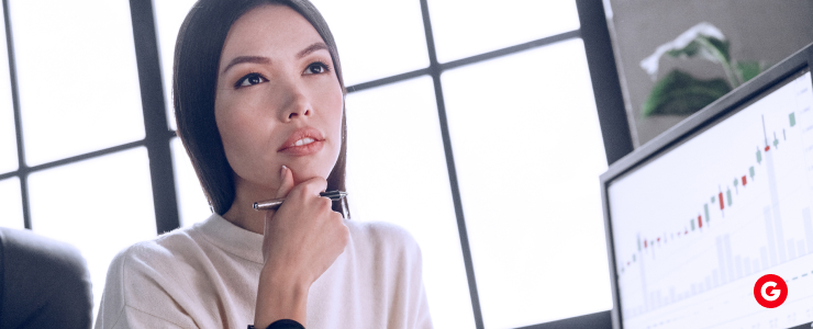 A woman analyzes a trading chart on her computer screen, focusing on AI and forex trading data.
